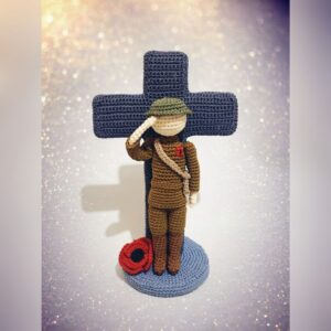 crochet soldier in front of crochet cross with poppy