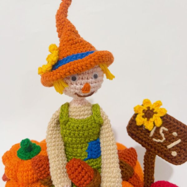 crochet scarecrow with crochet pumpkins, sunflowers, sign, leaves and a mushroom
