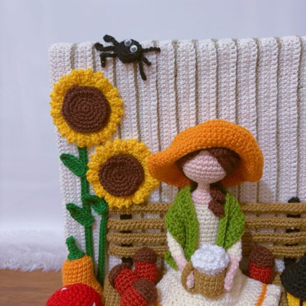 crochet Fall or Autumn decoration with a girl sitting on a bench drinking coffee, surrounded by pumpkins, mushroom, spider, barrel, sunflower