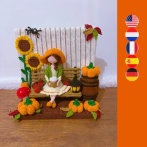crochet lady sitting on bench with coffee, surrounded by sunflowers, pumpkins, a barrel, leafs, mushrooms