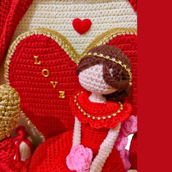 crochet lady in red dress in crochet Valentine setting with crochet hearts, roses, gift boxes and curtains