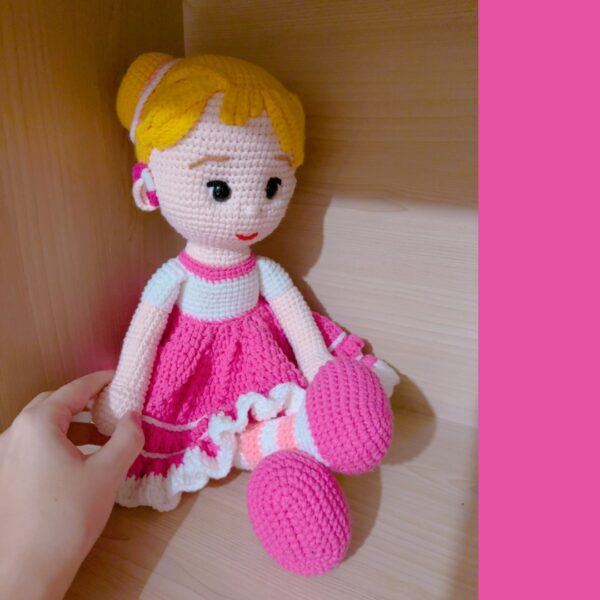 crochet doll wearing a pink dress and hearing aids