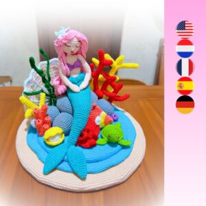 crochet mermaid sitting on crochet rock surrounded by crochet coral reef (corals, fish, turtle, sea shells, water, sand)
